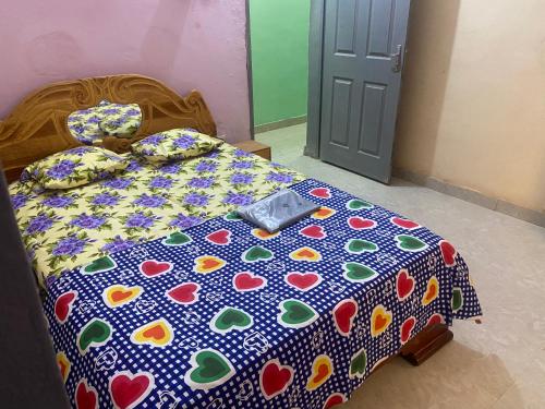 a bed with a polka dot bedspread with hearts on it at Appartement et Chambres in Bamako