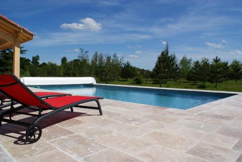 a red chair sitting next to a swimming pool at Chateau De Grenier Apartment in Saint-Léger