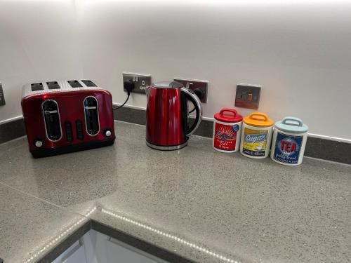 a counter top with a toaster and cans on it at Hatfield Haven - Modern 2-Bed Retreat near Uni, Business Park & City Center, FREE Parking, Big savings on Longer Stays in Hatfield