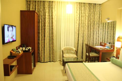 ein Hotelzimmer mit einem Bett, einem Tisch und einem Schreibtisch in der Unterkunft Hotel Green Olive in Aurangabad