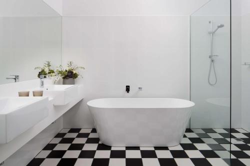 a white bathroom with two sinks and a tub at Rydges Hobart in Hobart