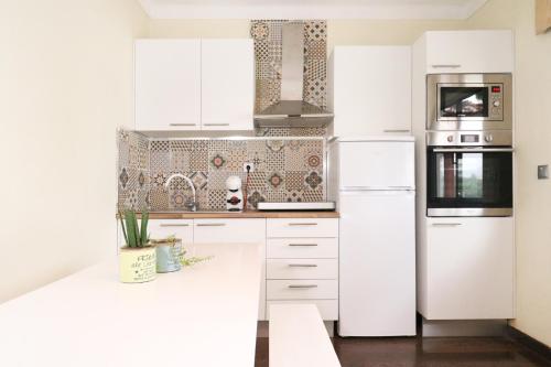 a white kitchen with white cabinets and appliances at Charme Lusitano Countryside Experiences in Inguias