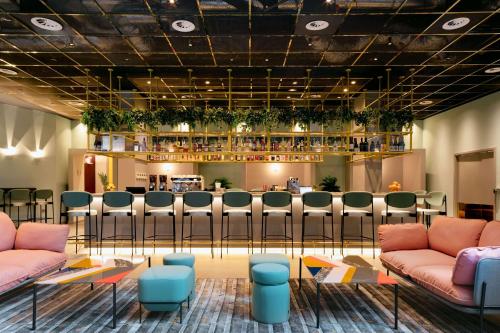 un vestíbulo con un bar con sillas rosas y azules en YOTEL London City, en Londres