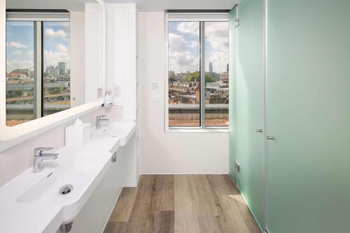 a bathroom with two sinks and a window at YOTEL London City in London
