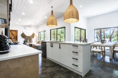 an open kitchen with white cabinets and a table at Rambles Landing - get lost amongst the trees - NEW in Margaret River Town