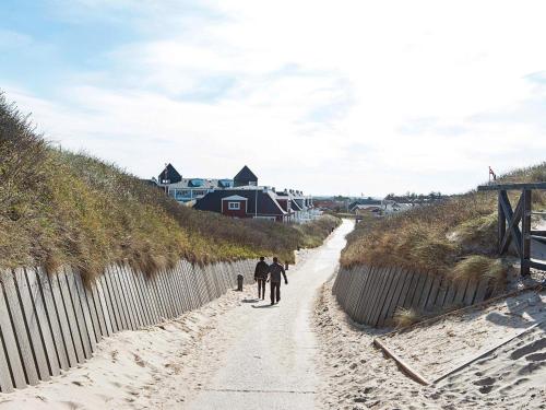 dos personas caminando por un camino de arena a la playa en 6 person holiday home in Ringk bing, en Ringkøbing