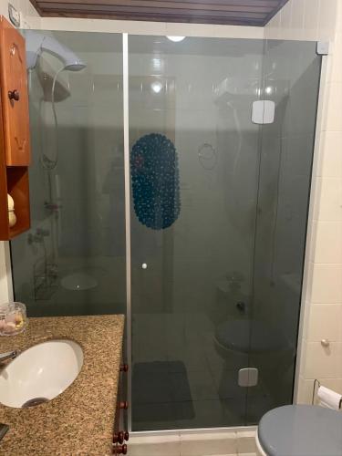 une douche en verre dans une salle de bain avec un lavabo dans l'établissement Charmoso Apartamento em Gramado, à Gramado