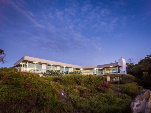 a building on top of a hill with bushes at Horizons House - spacious, ocean + bush views, peaceful in Margaret River Town