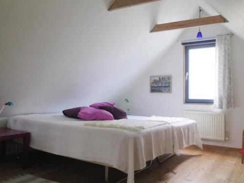 a white bed with purple pillows in a room at 2 person holiday home in Garsnäs-By Traum in Gärsnäs