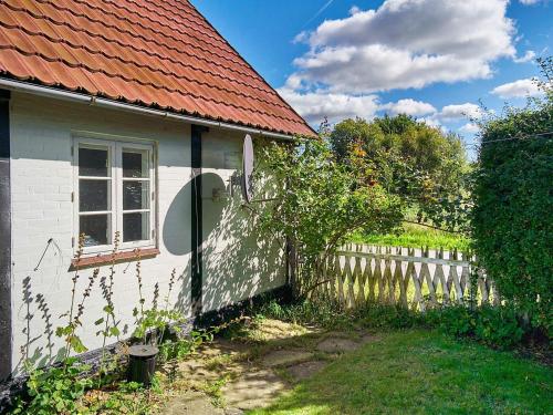 een wit huis met een rood dak en een hek bij 5 person holiday home in Aakirkeby in Åkirkeby