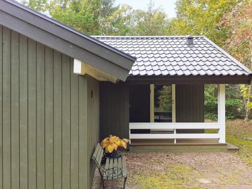 un bâtiment vert avec un banc et une terrasse couverte dans l'établissement 6 person holiday home in Frederiksv rk, à Frederiksværk