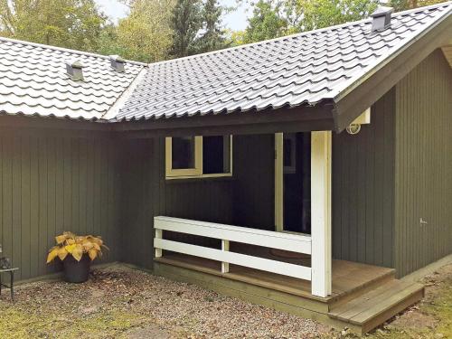 een groen huis met een veranda en een wit hek bij 6 person holiday home in Frederiksv rk in Frederiksværk
