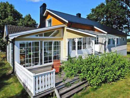 una pequeña casa blanca y amarilla con porche en 6 person holiday home in MELLERUD, en Mellerud