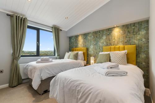 a bedroom with two beds and a window at Ael-Y-Bryn - Luxury Lodge, Hot Tub, Three En-Suite Bedrooms in Penally