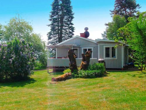 una pequeña casa en un patio con un tronco de árbol en 4 person holiday home in KRISTIANSTAD en Kristianstad