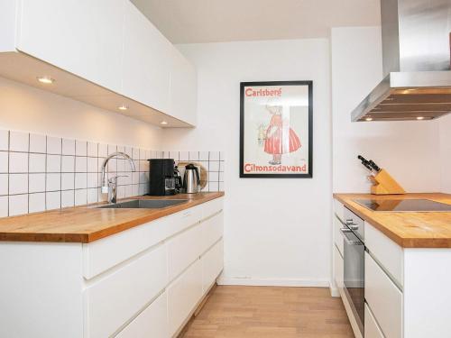 une cuisine avec des placards blancs et une photo sur le mur dans l'établissement 6 person holiday home in Skagen, à Skagen
