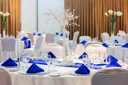 a set of tables with white chairs and blue napkins at Fiesta Royale Hotel in Accra