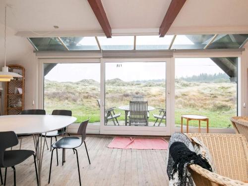 ein Wohnzimmer mit einem Tisch und Stühlen sowie einem großen Fenster in der Unterkunft 6 person holiday home in Pandrup in Rødhus