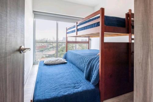 a bedroom with a bunk bed with a blue bedspread at San Ángel UNAM 3 recámaras/2parking in Mexico City