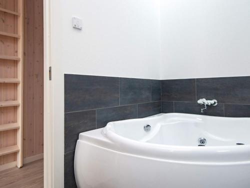 y baño con bañera blanca y azulejos negros. en 8 person holiday home in B rkop en Børkop