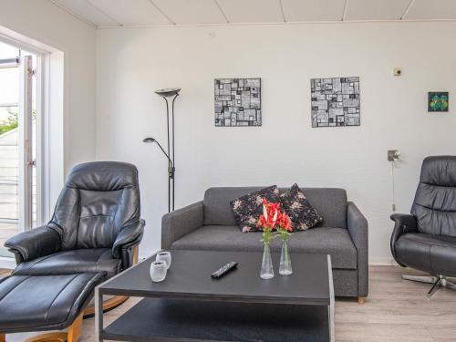 een woonkamer met 2 stoelen, een bank en een tafel bij 4 person holiday home in R m in Sønderby