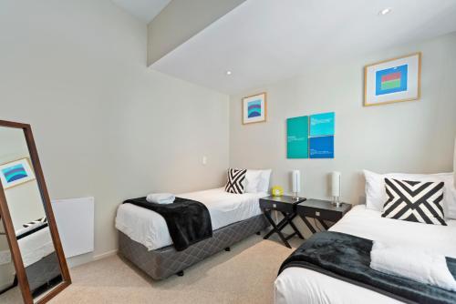 a bedroom with two beds and a mirror at Two Views Taupo Apartment in Taupo