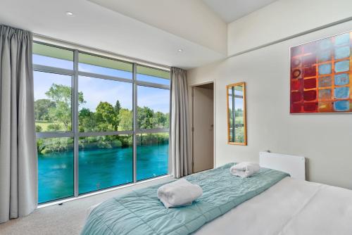 um quarto com uma cama e uma grande janela em Two Views Taupo Apartment em Taupo