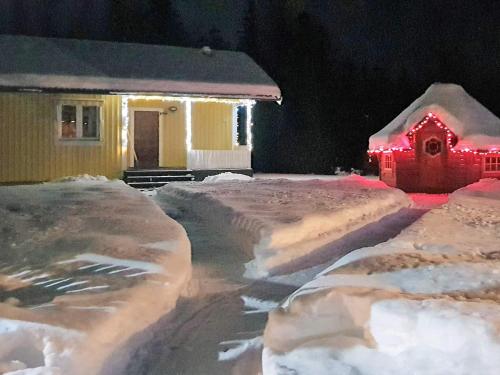 una casa cubierta de nieve por la noche con luces rojas en 4 person holiday home in LJUSDAL, en Ljusdal