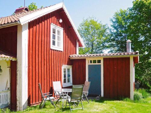 een rood huis met stoelen en een tafel ervoor bij 5 person holiday home in LAMMHULT in Lammhult