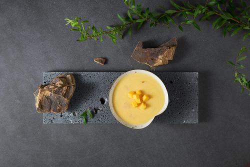 a bowl of yellow liquid on a table with some food at Runaway Cow Winery Retreat in Yantai