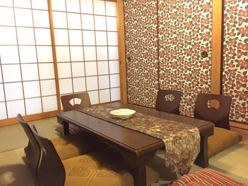 een eetkamer met een tafel en stoelen bij Yumeji Guest House in Osaka