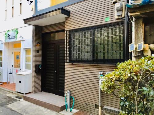 een huis met een zwarte deur aan de zijkant bij Yumeji Guest House in Osaka