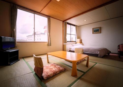 a room with a bed and a table and a bed and a bedroom at Oyado Kinkiyu in Teshikaga