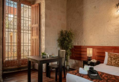 1 dormitorio con mesa, cama y escritorio en La Casa de Melgar, en Arequipa