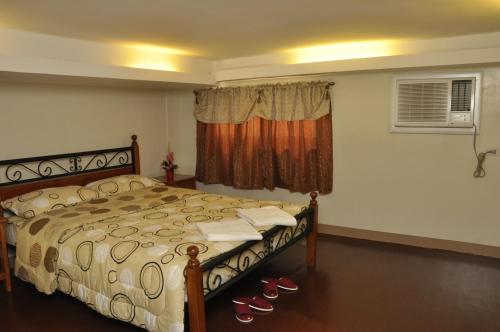 a bedroom with a bed with shoes in front of a window at Pal-Watson Apartments in Mactan