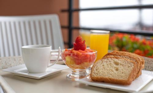 a table with a breakfast of fruit and bread and a cup of coffee at Hotel Rosales Boutique in Neiva