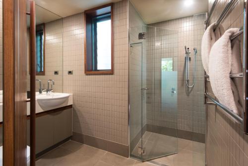 a bathroom with a glass shower and a sink at Yacht Club Villas on Hamilton Island by HIHA in Hamilton Island
