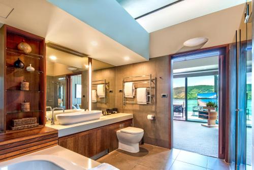 a bathroom with a tub and a toilet and a sink at Yacht Club Villas on Hamilton Island by HIHA in Hamilton Island