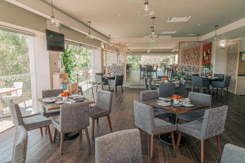 a dining room with tables and chairs and windows at Holiday Inn Tlaxcala by IHG in Tlaxcala de Xicohténcatl