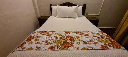a bed with a floral comforter on it at Hotel de MariaCENTRO in San Cristóbal de Las Casas