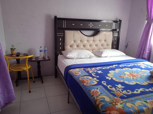 Trivadoh Syariah Hotel في Padangpanjang: غرفة نوم بسرير وطاولة مع كرسي