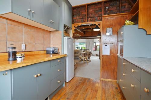 a kitchen with blue cabinets and wooden floors at Snow Chalet - Fairlie Holiday Home in Fairlie