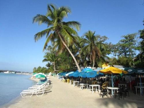 a beach with tables and chairs and umbrellas at Self-checking-Fast internet-Alexa-Smart-Tv-AC-Hot Water in Ensanche Ozama