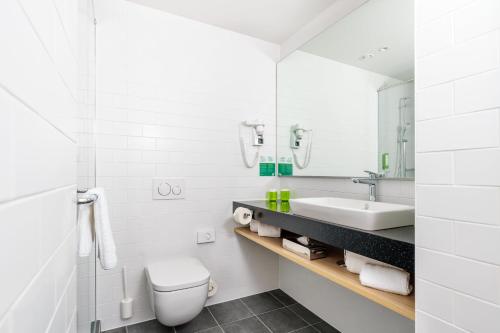 a white bathroom with a sink and a toilet at Clarion Hotel Vienna South in Vienna