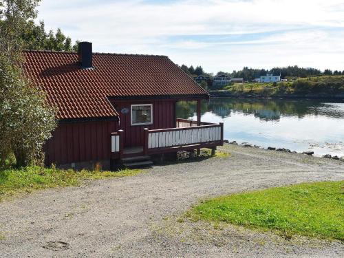 a small red house with a balcony next to a lake at 6 person holiday home in Bud in Bud