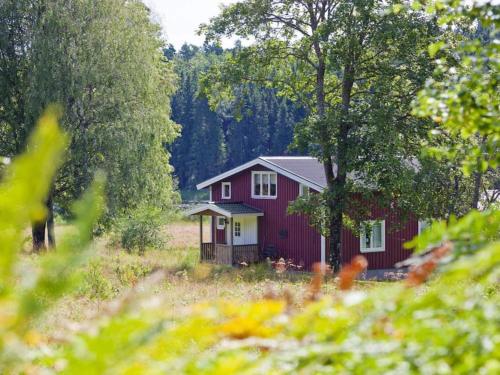 a red house in the middle of a field with trees at 6 person holiday home in Br landa in Brålanda