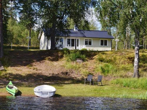 a house with two chairs and a boat on the water at 4 person holiday home in GISLAVED in Gislaved
