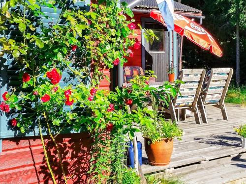 um deque com cadeiras e flores e um guarda-sol em 6 person holiday home in BLID em Blidö
