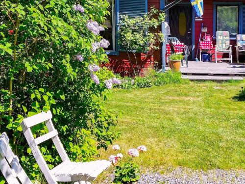 uma cadeira branca sentada num quintal ao lado de um arbusto em 6 person holiday home in BLID em Blidö