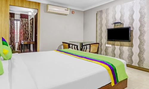 a bedroom with a white bed and a tv at Treebo Symphony Hotels And Resorts Angamally in Kizhake Chālakudi
